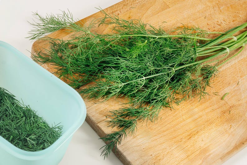a wooden cutting board topped with green herbs