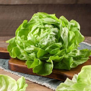 a bunch of lettuce sitting on top of a wooden cutting board