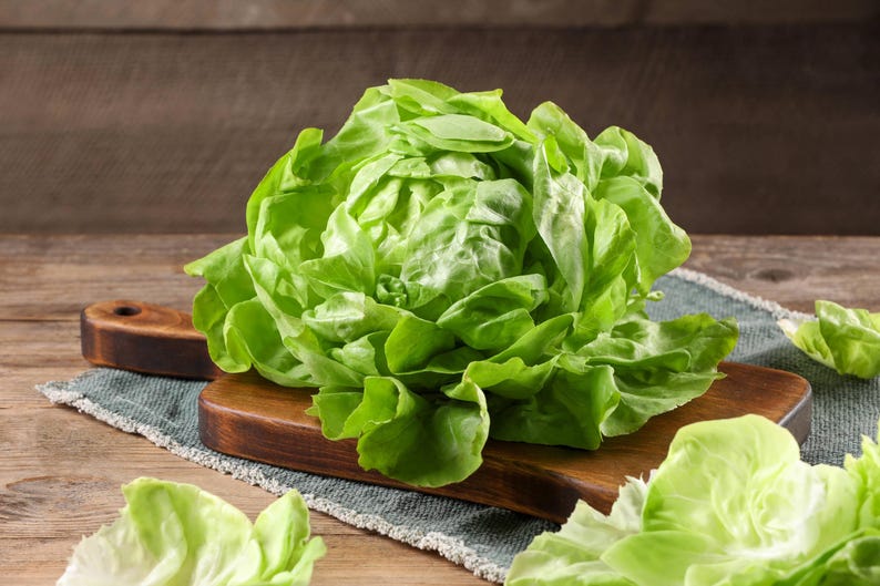 a bunch of lettuce sitting on top of a wooden cutting board