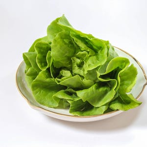 a white bowl filled with lettuce on top of a table