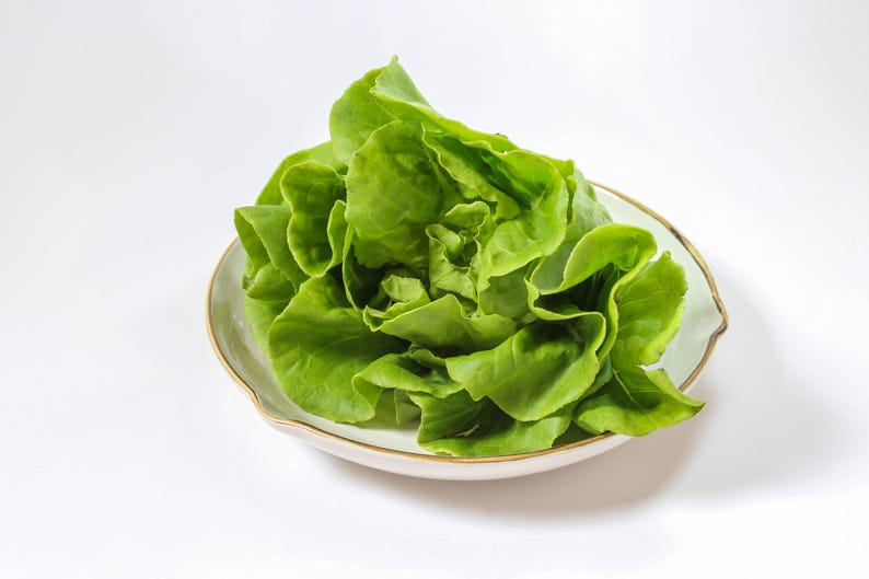a white bowl filled with lettuce on top of a table