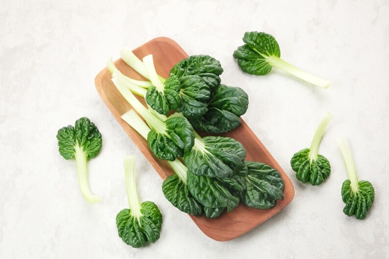 a wooden cutting board topped with green leafy vegetables