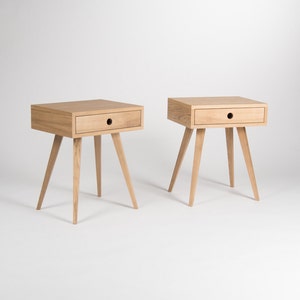 May include: Two wooden bedside tables with a single drawer and four legs. The tables are made of light wood and have a simple, modern design.