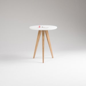 May include: A white round side table with a wooden tripod base. The table is on a white background.