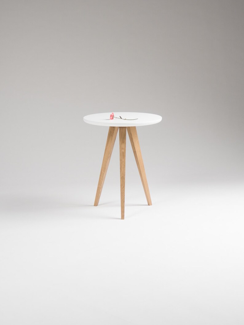 May include: A white round side table with a wooden tripod base. The table is on a white background.