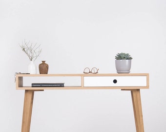 May include: A light wood console table with a white drawer and a shelf. The table has a black knob on the drawer and is decorated with a small potted succulent, a vase with twigs, and a small wooden vase.