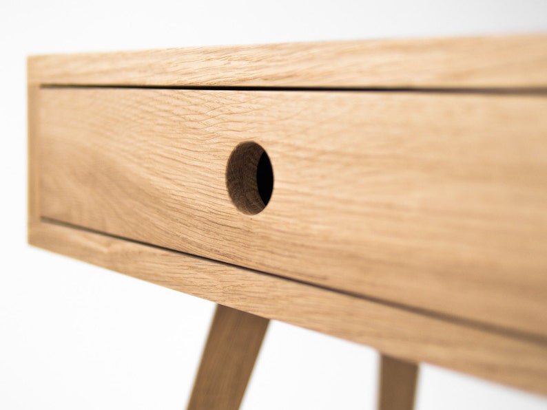 May include: A light wood bedside table with a single drawer and a round knob. The bedside table has a simple, modern design and is ideal for a bedroom.