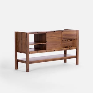 May include: A wooden cabinet with a sliding door, two drawers, and a lower shelf. The cabinet is made of walnut wood and has a natural finish.