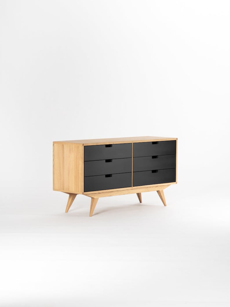 May include: A six-drawer dresser with black drawers and a light wood frame. The dresser has tapered legs and a mid-century modern style.