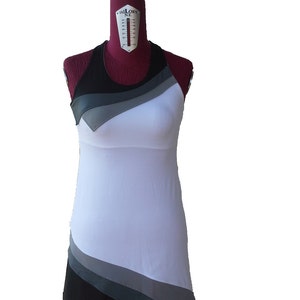 May include: A white sleeveless dress with black and gray geometric patterns. The dress has a fitted bodice and a flowing skirt.