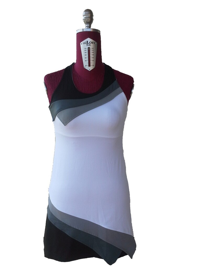 May include: A white sleeveless dress with black and gray geometric patterns. The dress has a fitted bodice and a flowing skirt.