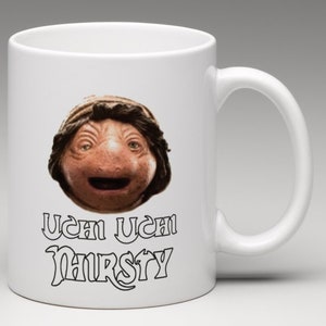 May include: White ceramic mug with a brown and black image of a character from the movie "The Last Starfighter" with the text "Uch Uch Nursty" printed on the mug.