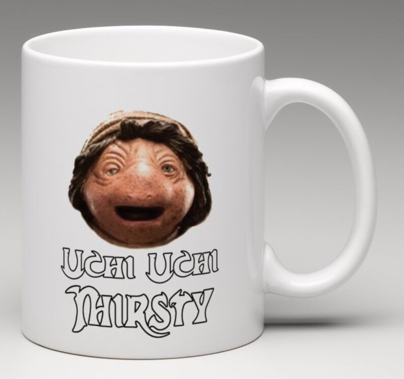 May include: White ceramic mug with a brown and black image of a character from the movie "The Last Starfighter" with the text "Uch Uch Nursty" printed on the mug.