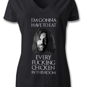 May include: Black V-neck t-shirt with a humorous graphic. The shirt features a grayscale image of a man's face and the text: "I'M GONNA HAVE TO EAT EVERY FUCKING CHICKEN IN THIS ROOM."