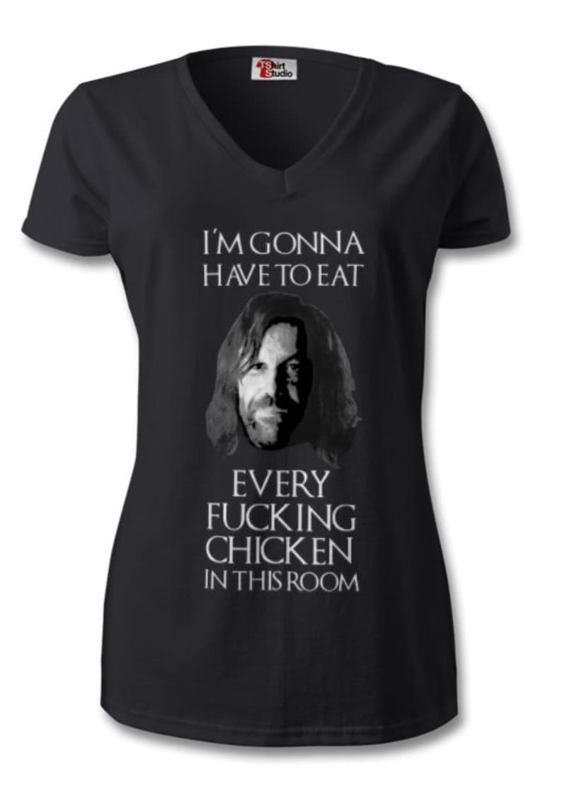 May include: Black V-neck t-shirt with a humorous graphic. The shirt features a grayscale image of a man's face and the text: "I'M GONNA HAVE TO EAT EVERY FUCKING CHICKEN IN THIS ROOM."
