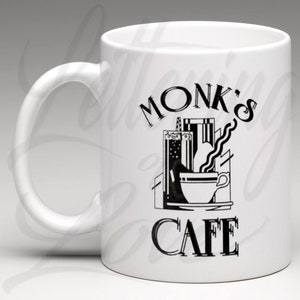 May include: White ceramic mug with a black graphic of a stylised coffee cup and the text "Monk's Cafe".