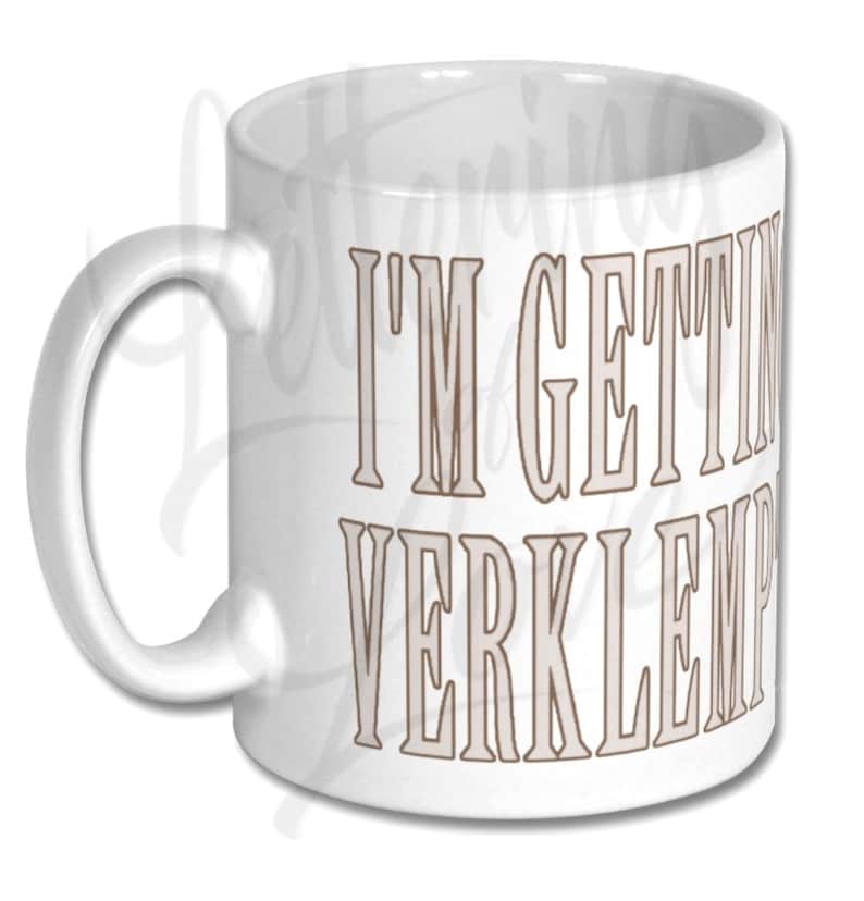Puede incluir: Taza de caf&eacute; de cer&aacute;mica blanca con un contorno marr&oacute;n del texto "I'm getting verklempt" impreso en la parte delantera.