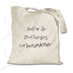 Pu&ograve; includere: Una borsa tote in tela bianca con testo scritto a mano in nero che recita "Nolite te Bastardes carborundum".