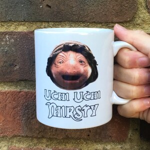 May include: White ceramic mug with a cartoon image of a character from the movie Labyrinth. The text "Uch Uch Thirsty" is printed below the image.