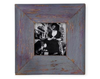 May include: Square picture frame with a distressed, weathered finish in shades of gray and purple. The frame surrounds a black and white photograph of a woman wearing a sash that reads "Votes for Women".