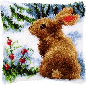 May include: A brown bunny rabbit sitting in a snowy winter scene with green bushes and red berries. The bunny is facing to the left and has a fluffy tail. The background is a light blue and white color.