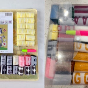 Op de afbeelding: Een naaldvilten set met een kat met bloemen. De set bevat een canvas, garen, naalden en instructies. Het garen is georganiseerd in kleine plastic containers met letters en nummers.