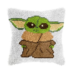 May include: A white plush cushion featuring an embroidered image of a character from the Star Wars franchise. The character is green and brown with large eyes and a pointed head.