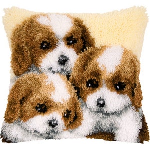 Pode incluir: Uma almofada decorativa quadrada com um design tufado de três cachorros Cavalier King Charles Spaniel. Os cachorros têm pelo castanho e branco, olhos e nariz pretos. O fundo é de cor amarelo claro.