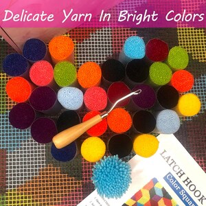May include: A set of colorful yarn in various shades, including red, orange, yellow, green, blue, purple, and black. The yarn is arranged in a circle around a wooden latch hook tool. The yarn is labeled "Latch Hook Color Square".