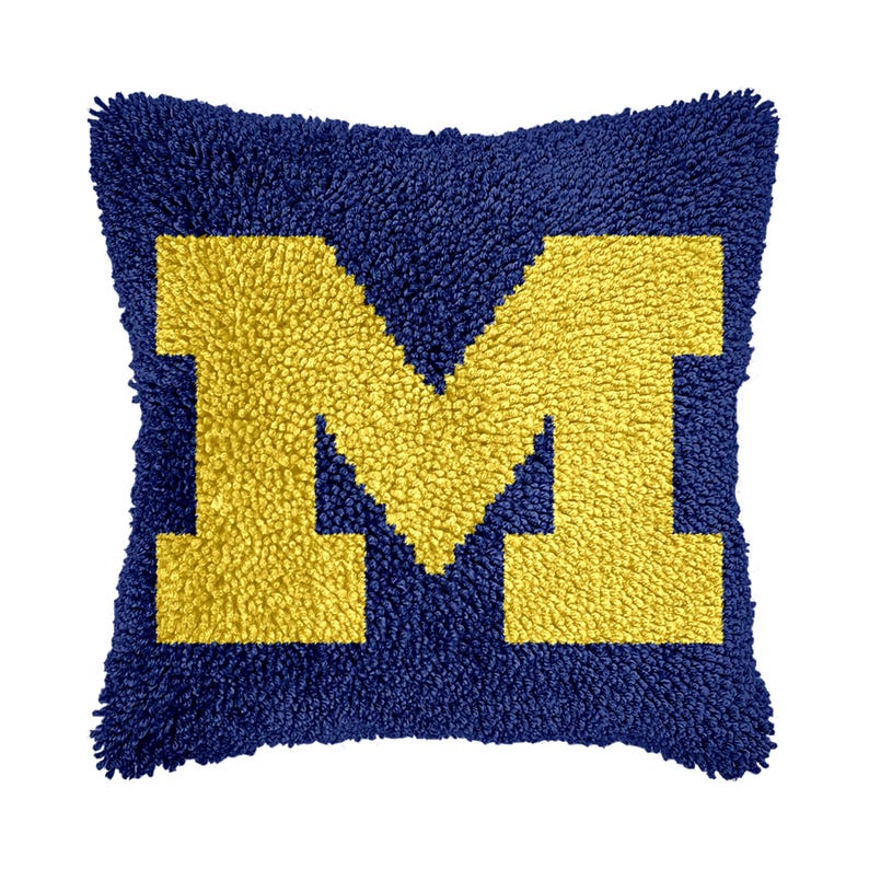 May include: A blue and yellow throw pillow with a large yellow "M" in the center.