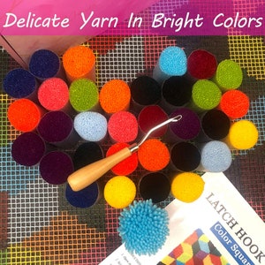 May include: A set of colourful yarn in various shades, including red, orange, yellow, green, blue, purple, and black. The yarn is arranged in a circle around a wooden latch hook tool and a blue latch hook rug. The text "Latch Hook Color Square" is visible on a white card.