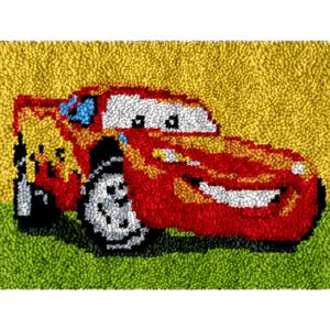 以下が含まれることがあります： 炎、白いタイヤ、青い窓が付いた、笑顔の赤いレーシングカーが描かれた手作りのラグ。車は黄色の背景に配置され、下部には緑の草があります。ラグは、テクスチャード加工されたループパイルで作られています。
