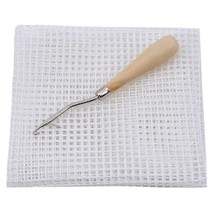 Peut inclure: Maille de toile blanche avec un crochet en bois et en métal. La maille est utilisée pour créer des tapis à crochet.