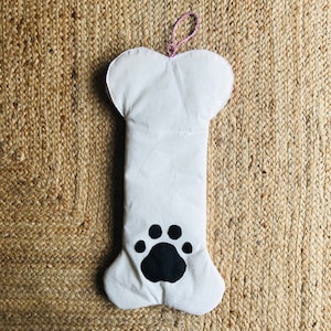 以下が含まれることがあります： 黒い足跡のデザインが施された白い布製の犬の骨の靴下