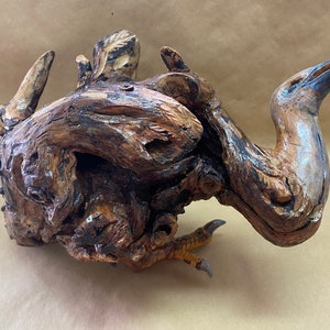 Peut inclure: Une sculpture en bois d'un oiseau au long cou et à la surface texturée et détaillée. L'oiseau est sculpté dans un seul morceau de bois et a une couleur brune naturelle.