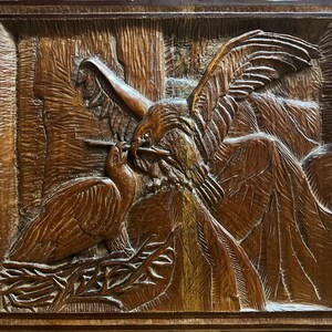 Peut inclure: Une sculpture en bois représentant deux oiseaux, l'un avec ses ailes déployées, l'autre dans un nid. La sculpture est détaillée et réaliste, avec des détails complexes dans les plumes et le nid.