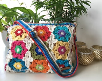 May include: A colorful crocheted bag with a long strap. The bag is made of squares with different colored flowers in the center. The strap is red, blue, and white. The bag has the text "Love Loops" on the bottom left corner.