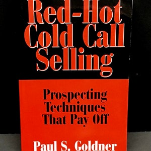 May include: Red-Hot Cold Call Selling: Prospecting Techniques That Pay Off by Paul S. Goldner. A book cover with a red and black design. The title is in large red letters on a black background. The subtitle is in black letters on a red background.