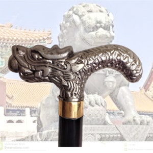 May include: A silver dragon head cane handle with intricate details. The handle is attached to a black wooden shaft.