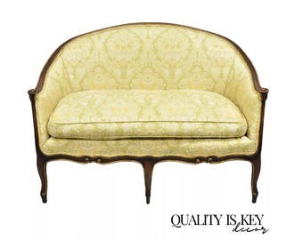 May include: A small, light green patterned loveseat with a curved back and wooden legs. The loveseat has a gold trim around the edges.