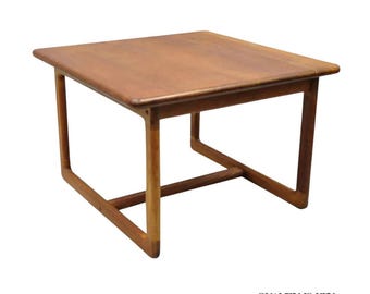 May include: A square, mid-century modern coffee table made of light brown wood. The table has a simple design with a flat top and four legs. The legs are connected by a horizontal support beam. The text "QUALITY IS KEY" is in the bottom right corner.