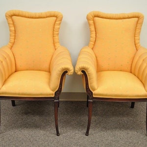 May include: A pair of yellow upholstered armchairs with wooden frames and scrolled arms. The chairs have a tufted back and a patterned fabric.