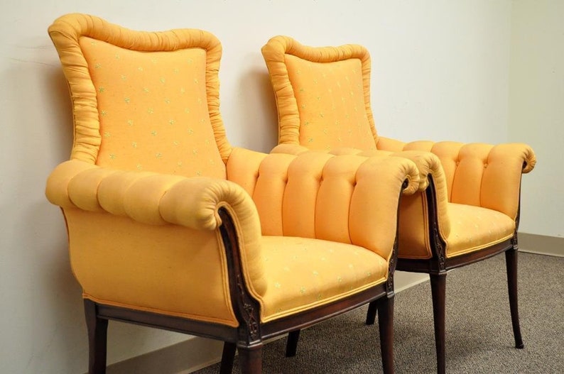 May include: A pair of yellow upholstered armchairs with tufted backs and rolled arms. The chairs have wooden frames and legs.