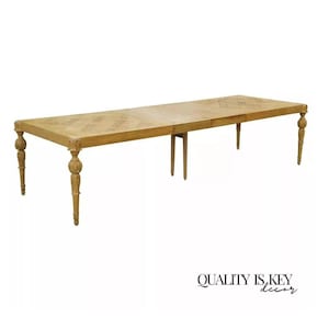 May include: A light wood dining table with a parquet top and turned legs. The table is extended to its full length, showing the leaf extension mechanism.