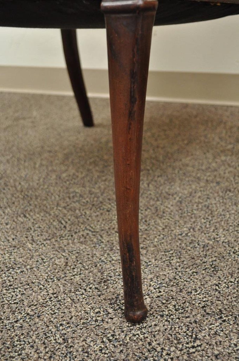 May include: Close-up of a dark brown wooden chair leg with a slightly rounded bottom.