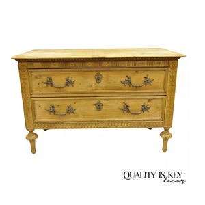 May include: A two-drawer dresser with carved details and brass hardware. The dresser is made of light wood and has a simple, elegant design.