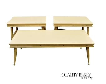 May include: A set of three mid-century modern tables with light wood grain tops and tapered legs. The tables have a rectangular shape and are arranged in a group. The text "QUALITY IS KEY decor" is at the bottom.