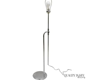 May include: A chrome floor lamp with a simple design. The lamp has a single light bulb and a round base.