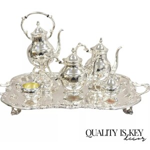 May include: Silver tea set with a teapot, creamer, sugar bowl, and tray. The set is on a white background.