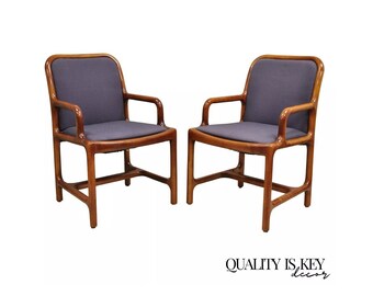 May include: Two wooden chairs with dark brown frames and gray fabric upholstery. The chairs have a simple, modern design with curved armrests.